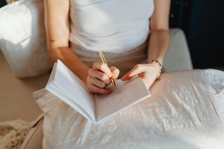 Close-up of a woman writing in a journal while sitting comfortably indoors.